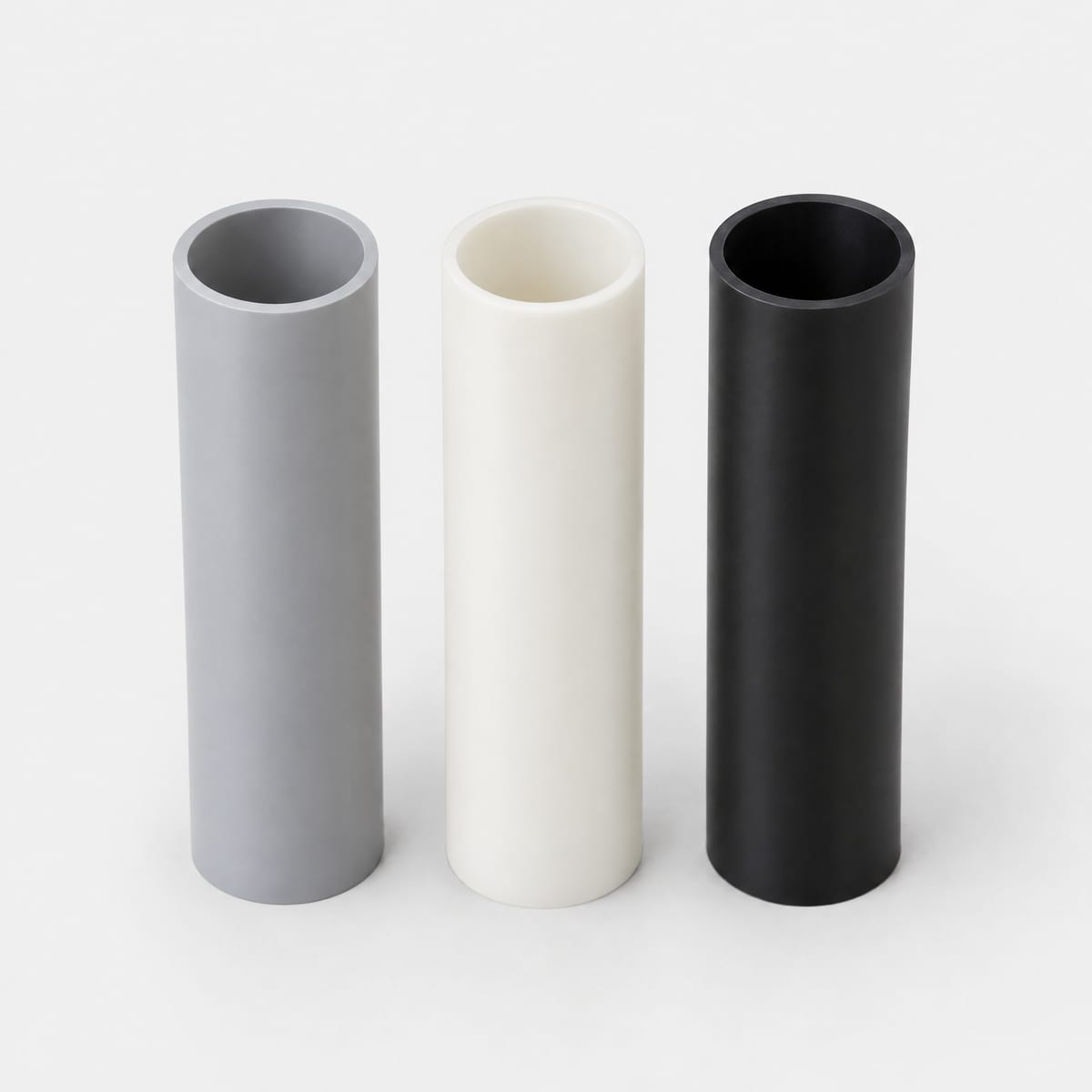 Plastic cores for rolls in grey PVC, white PP and black HDPE side by side